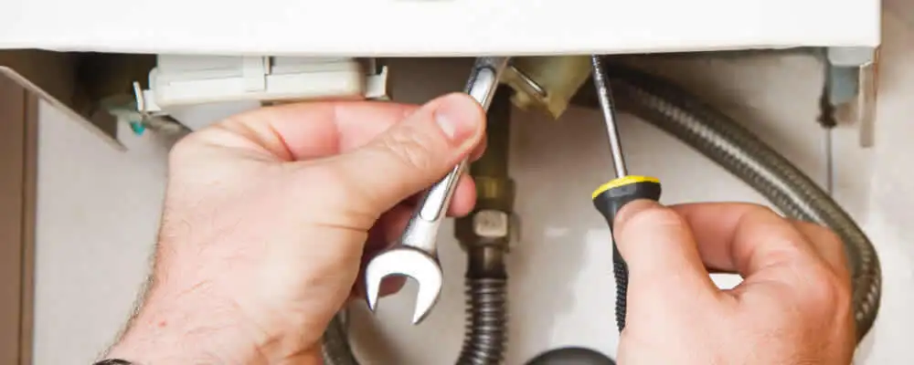Boiler repair technician tightening pipe fittings and connections in Colorado Springs, CO