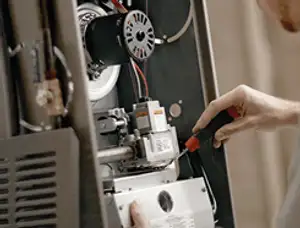 Furnace repair technician inspecting internal components and wiring in Colorado Springs, CO