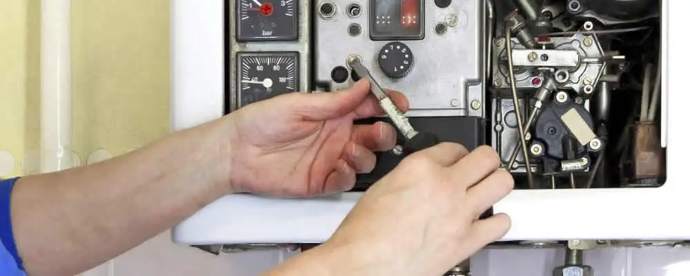 Heating repair technician adjusting boiler controls and components in Colorado Springs, CO
