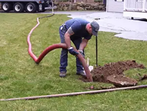 Septic pumping technician servicing a residential septic tank with a vacuum hose in Colorado Springs, CO