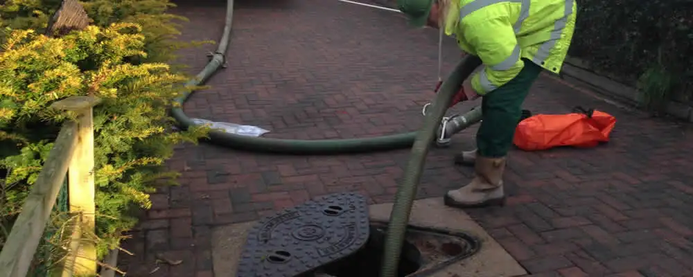 Septic tank cleaning technician servicing a septic tank with a vacuum hose in Colorado Springs, CO