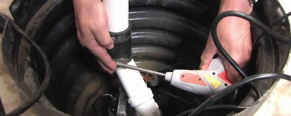 Sump pump installation technician connecting PVC discharge piping in Colorado Springs, CO