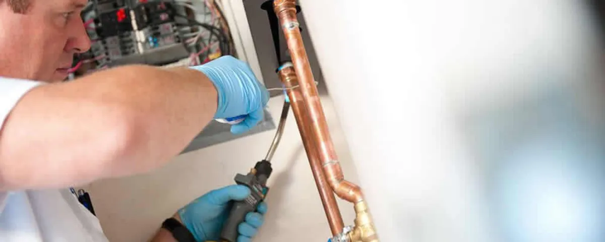 Water heater repair technician testing copper pipe connections and controls in Colorado Springs, CO
